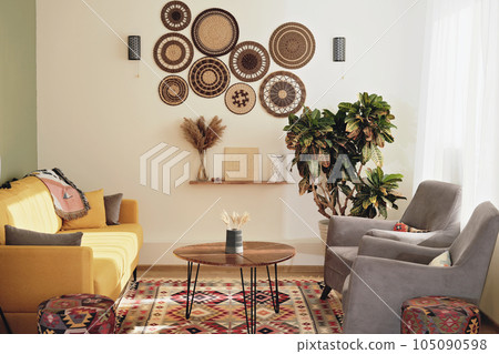 part of boho style living room with wooden coffee table and yellow sofa. cozy apartment decorated with plants. part of boho style living room with wooden coffee table and yellow sofa. cozy apartment decorated with plants. 105090598