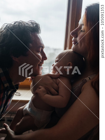 Mom and dad newborn. Caring and loving parents kiss the child on both cheeks. The concept of loving parents, the manifestation of emotions and a responsible attitude towards motherhood and fatherhood 105091353