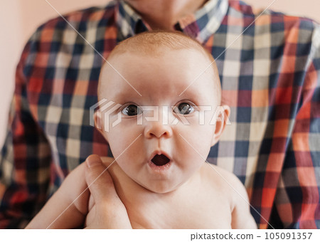 Newborn surprise. The little girl opened her eyes and mouth wide in surprise. The concept of loving parents and ensuring the safety of children. Curiosity and wonder Newborn surprise. The little girl opened her eyes and mouth wide in surprise. The concept of loving parents and ensuring the safety of children. Curiosity and wonder 105091357