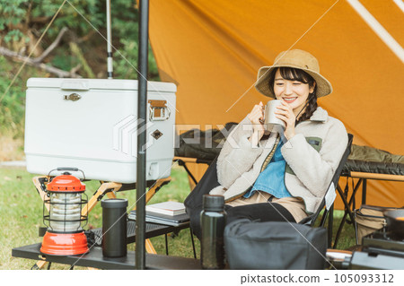 Young female camper (drinking) camping solo at campsite 105093312