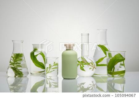 A set of transparent glassware filled with green seaweed and water. Cosmetic bottle in pastel color with empty label is featured. Research science content A set of transparent glassware filled with green seaweed and water. Cosmetic bottle in pastel color with empty label is featured. Research science content 105094067