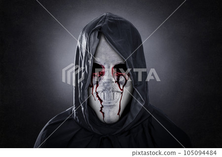Spooky figure in blood with hooded cape over dark misty background 105094484