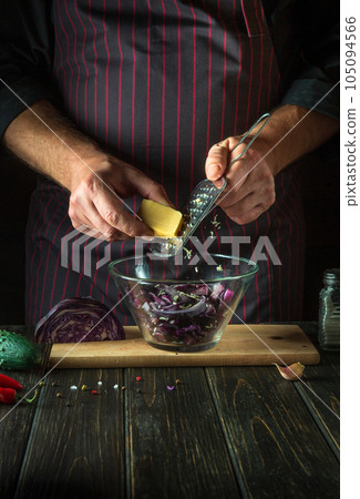 Chef adds cheese to a fresh red cabbage salad in a restaurant kitchen. Cooking healthy or vegetarian food Chef adds cheese to a fresh red cabbage salad in a restaurant kitchen. Cooking healthy or vegetarian food 105094566