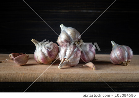Garlic cloves and onions on a wooden cutting board before adding to food. Copy space. The idea of cooking spicy Asian food with garlic. Garlic cloves and onions on a wooden cutting board before adding to food. Copy space. The idea of cooking spicy Asian food with garlic. 105094590