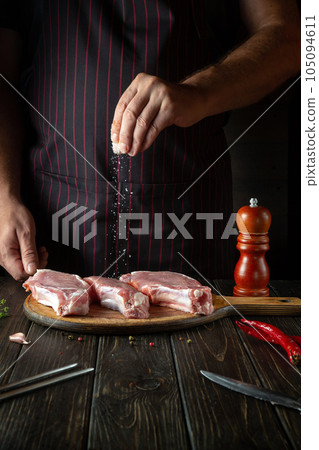The chef sprinkles raw ribs with salt. The concept of cooking delicious food for the hotel or restaurant 105094611