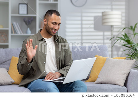 Happy and smiling young hispanic man talking remotely with his psychologist doctor, waving hand to camera, feeling good mentally. 105096164