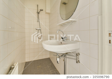 a bathroom with a sink, mirror and towel rack on the wall next to it is a white tiled floor 105096790