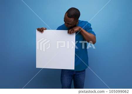 young attractive african man dressed in basic t-shirt holding a white poster mockup for advertising young attractive african man dressed in basic t-shirt holding a white poster mockup for advertising 105099062