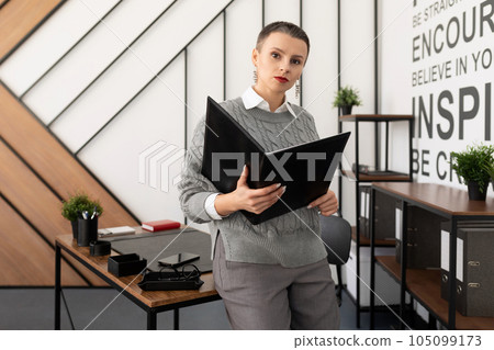successful startup leader woman standing in the office holding a folder successful startup leader woman standing in the office holding a folder 105099173