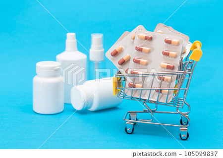 Pills and Capsules in Shopping Cart on Blue Background Pills and Capsules in Shopping Cart on Blue Background 105099837