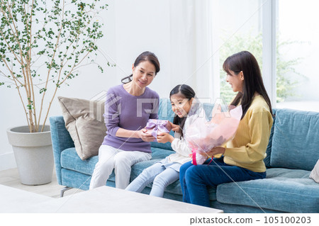 Granddaughter giving a present to grandma 105100203