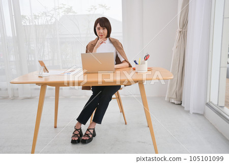 在室內辦公桌前使用筆記本電腦工作的年輕女性 在室內辦公桌前使用筆記本電腦工作的年輕女性 105101099