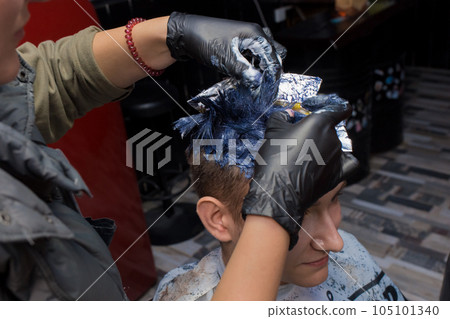 Close-up the hands of a girl of an experienced salon master in gloves are engaged in dyeing hair in color, stylish fashionable hairstyle of the client 105101340