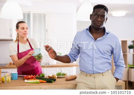 Woman giving container with salad to her disappointed husband 105101710