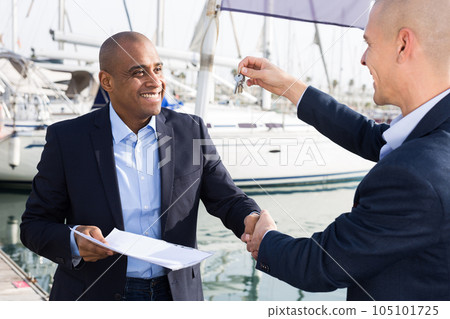 Latin American men with documents and keys near the yachts in the port Latin American men with documents and keys near the yachts in the port 105101725