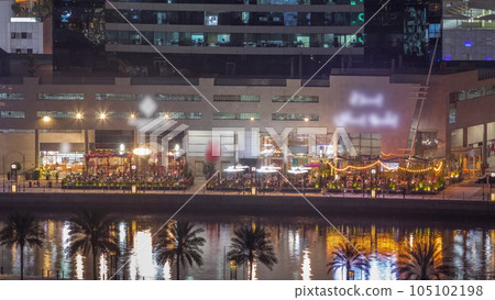 Walking promenade along water canal in Business Bay district of Dubai aerial night timelapse. 105102198