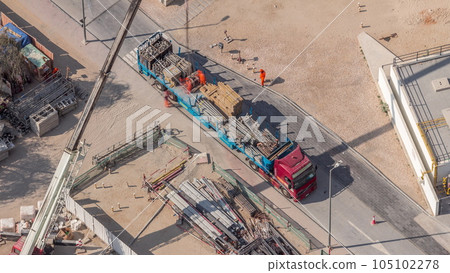 Unloading of building materials by crane at the construction site aerial timelapse 105102278