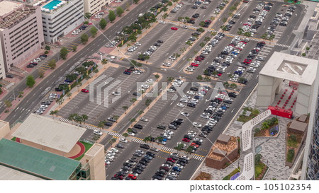 Aerial view of many colorful cars parked on parking lot with lines and markings for parking places all day timelapse. Dubai 105102354