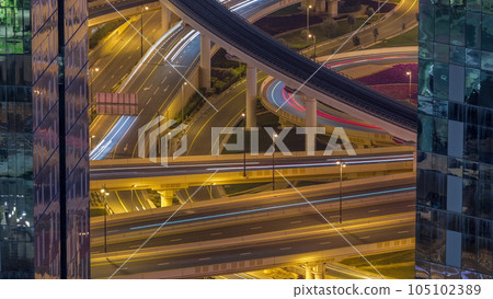 Aerial view from above to a busy road junction in Dubai night timelapse. 105102389