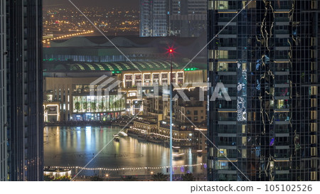 Aerial view of Dubai Fountain in downtown with palms in park next to shopping mall and souq all night timelapse, UAE 105102526