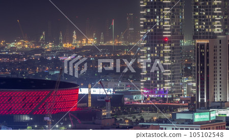 Aerial view to skyscrapers, houses and port Rashid on a background night timelapse, ships docking at sea port, UAE. 105102548