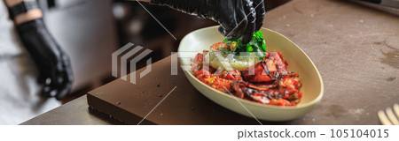 Professional chef is decorating ready meal with greens on restaurant kitchen 105104015