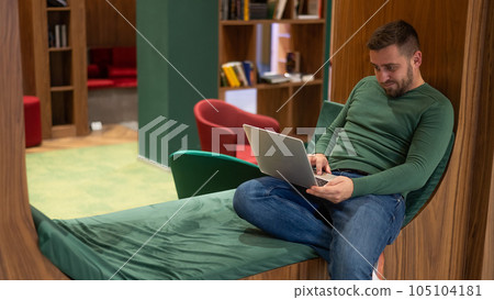 Caucasian bearded man working on laptop in modern coworking.  105104181