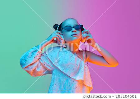 Happy school age girl, child wearing wireless headphones listening to music. Concept of childhood, emotions, kids fashion Happy school age girl, child wearing wireless headphones listening to music. Concept of childhood, emotions, kids fashion 105104501
