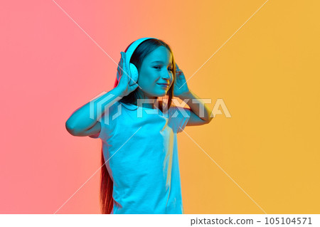 Happy school age girl, child wearing wireless headphones listening to music. Concept of childhood, emotions, kids fashion Happy school age girl, child wearing wireless headphones listening to music. Concept of childhood, emotions, kids fashion 105104571