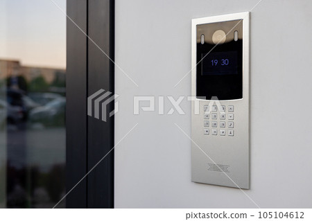 Doorbell with video camera and microphone, on the white wall of an apartment building, doorbell camera. 105104612