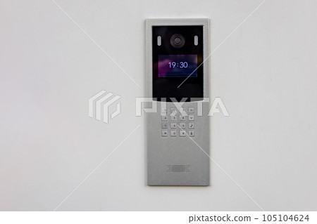 Doorbell with video camera and microphone, on the white wall of an apartment building, doorbell camera. Doorbell with video camera and microphone, on the white wall of an apartment building, doorbell camera. 105104624