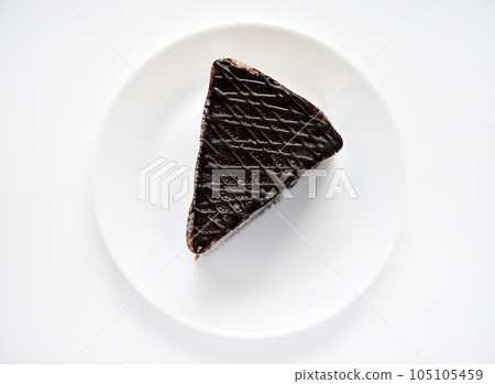 Chocolate cake on a white plate. A sweet snack. Sweetness for tea. 105105459