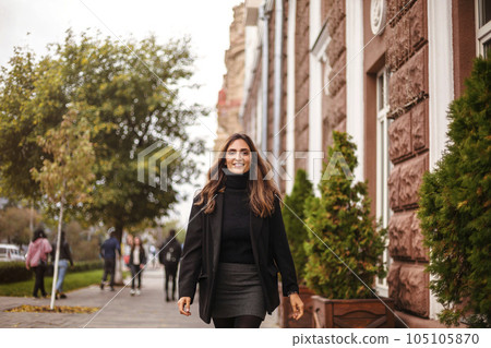 Young fashionable confident woman walking on city street outdoors 105105870