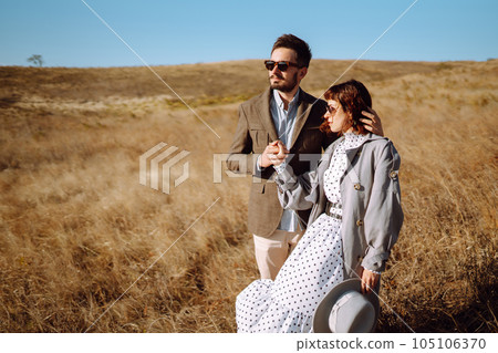 Stylish and loving couple enjoying each other outdoors. Stylish couple walking and hugging. 105106370