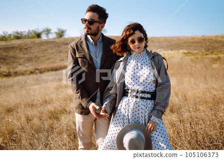 Stylish and loving couple enjoying each other outdoors. Stylish couple walking and hugging. 105106373