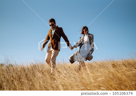 Stylish and loving couple enjoying each other outdoors. Stylish couple walking and hugging. 105106374