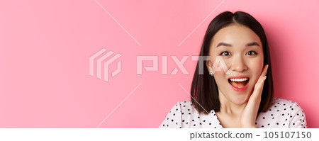 Beauty and lifestyle concept. Close-up of surprised and happy asian woman staring at camera amazed, gasping with disbelief, standing over pink background Beauty and lifestyle concept. Close-up of surprised and happy asian woman staring at camera amazed, gasping with disbelief, standing over pink background 105107150