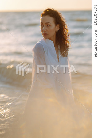 Stylish woman in elegant white dress posing near the sea. Summer time. Travel, weekend, relax. Stylish woman in elegant white dress posing near the sea. Summer time. Travel, weekend, relax. 105107179