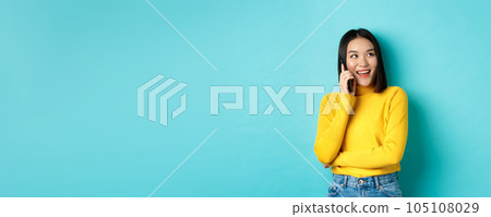 Stylish korean woman calling on phone, talking on smartphone and looking happy at upper right corner, smiling carefree, standing in relaxed pose over blue background Stylish korean woman calling on phone, talking on smartphone and looking happy at upper right corner, smiling carefree, standing in relaxed pose over blue background 105108029