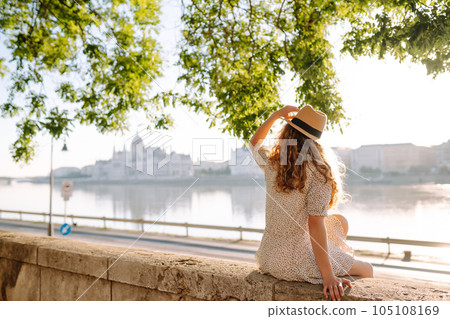 A beautiful young woman walks on the embankment. Tourism relax, youth, nature. 105108169