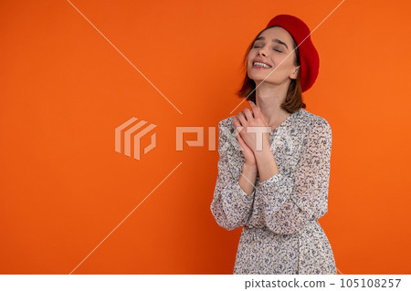 Happy pleased adult woman wearing elegant dress and red beret standing with closed eyes and smile Happy pleased adult woman wearing elegant dress and red beret standing with closed eyes and smile 105108257