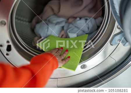 Woman washing dirty clothes, cleaning washing machine with rag in the laundry room. Woman washing dirty clothes, cleaning washing machine with rag in the laundry room. 105108281