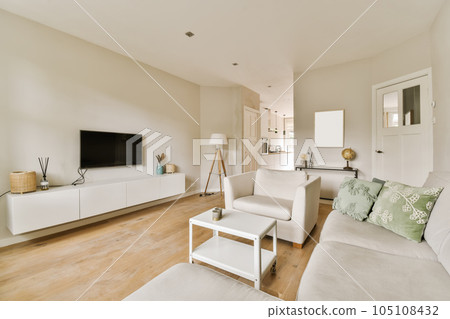 a living room with wood flooring and white couches in front of a flat screen tv on the wall 105108432