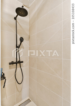 a shower with thermostaer and hand held in it's right arm, next to an air vent 105108433