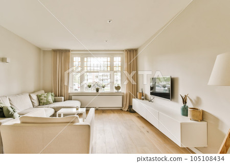 a living room with couches and a television set in front of the window on the wall is painted white 105108434