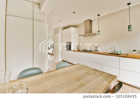 a kitchen and dining area in a house with white walls, wood flooring and an island table surrounded by blue chairs 105108435