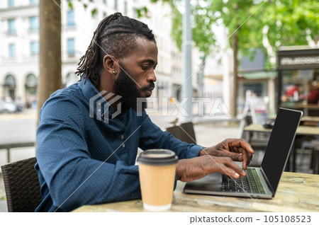 Dark-skinned young man working in a cafe outdoors 105108523