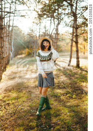 Lovely girl with a beautiful smile at sunset in the forest. The girl is dressed with a hat. Lovely girl with a beautiful smile at sunset in the forest. The girl is dressed with a hat. 105108828
