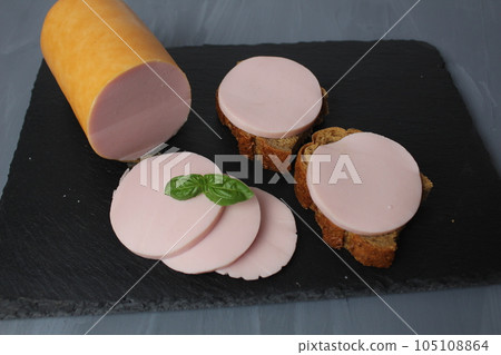 Boiled children's sausage for sandwiches Narean into pieces on a black board with green basil Boiled children's sausage for sandwiches Narean into pieces on a black board with green basil 105108864