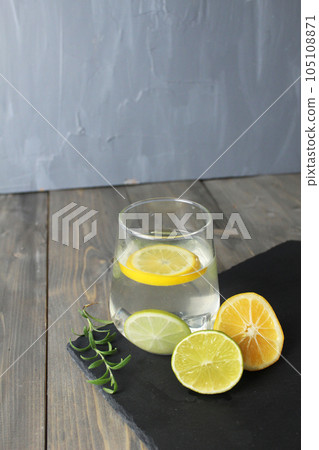 water with lemon homemade lemonade in a glass next to there are lemons with herb green rosemary on a black stand with a place for text. Healthy food drink drinks water with lemon homemade lemonade in a glass next to there are lemons with herb green rosemary on a black stand with a place for text. Healthy food drink drinks 105108871
